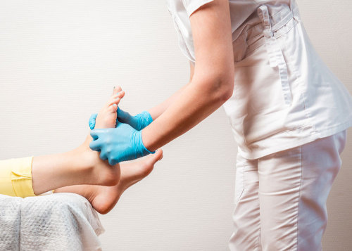 Podiartist treating persons feet wearing blue gloves