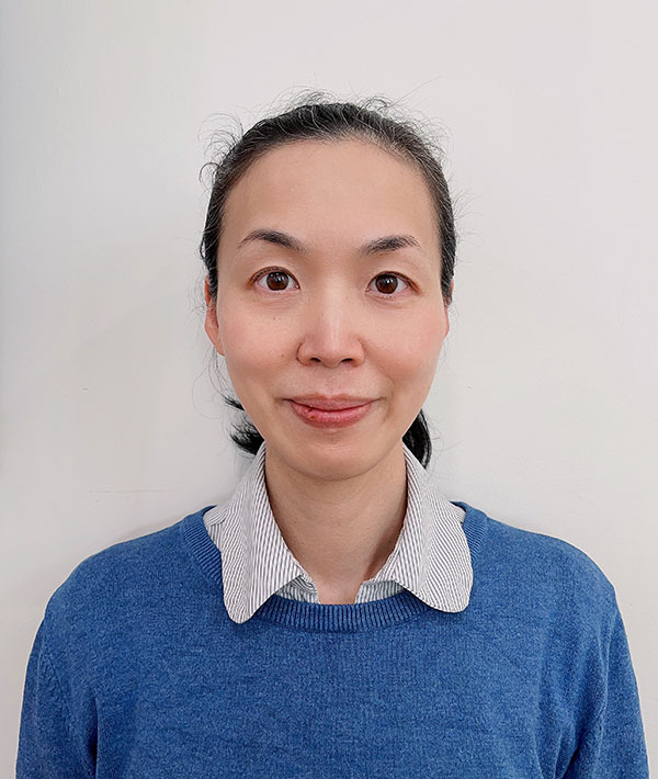 Asian woman wearing a blue knitted jumper and her hair in a ponytail